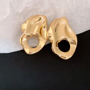 Primer plano de pendientes de metal dorado irregular con textura arrugada de moda