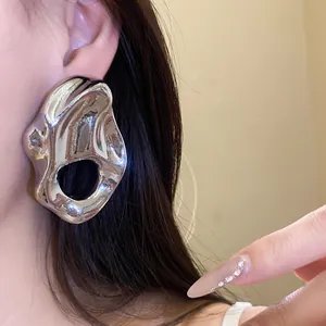 Primer plano detallado de aretes metálicos plateados irregulares usados por una modelo
