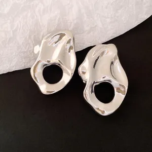 Primer plano de pendientes metálicos irregulares plateados con diseño plisado hueco