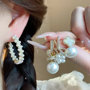 Macro view of elegant pearl and zircon earrings featuring floral and bow designs