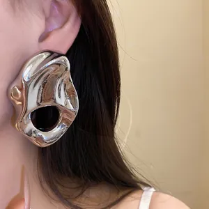 Primer plano detallado de un pendiente de metal plateado con diseño irregular y hueco