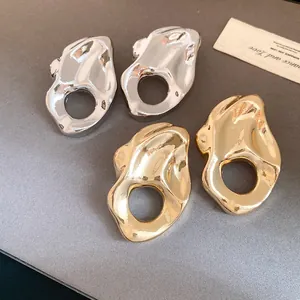 Vista detallada de pendientes metálicos huecos irregulares abstractos en oro y plata