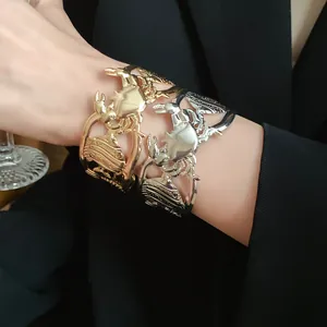 Detail view of metallic cutout crab and seashell cuff bracelets in gold and silver
