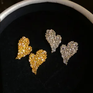 Dettaglio orecchini a lobo a cuore testurizzati oro e argento con zirconi brillanti