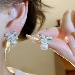 Close-up detail of elegant silver zircon butterfly earrings with white hanging pearls