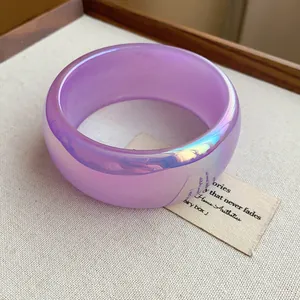 Detalle de un brazalete ancho iridiscente morado translúcido con efecto brillo