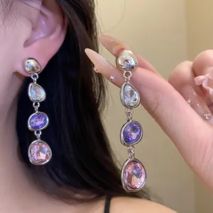 Dettaglio ravvicinato di eleganti orecchini a goccia con pendenti in cristallo viola e rosa