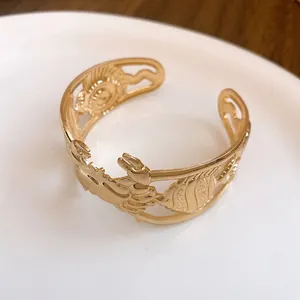 Detail view of gold hollow cuff bracelet featuring crab and fish sea life motifs