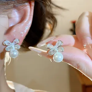 Detail showing elegant silver needle zircon flower earrings with a polished pearl drop