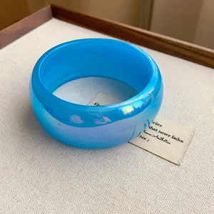 Primer plano de un brazalete ancho azul transparente irisado con efecto brillante