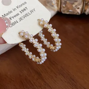 Close-up of elegant gold-plated hoop earrings featuring dainty pearls and zircon accents