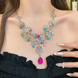 Détail d'un collier vintage fleuri en strass avec un grand pendentif goutte rose vif.