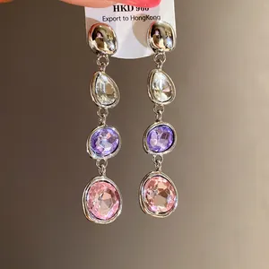 Dettaglio di orecchini di cristallo con pietre viola e rosa montati in argento