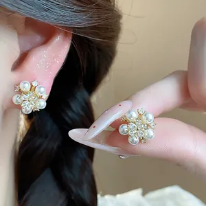 Detail view of elegant flower-shaped earrings with white pearls and sparkling zircons.