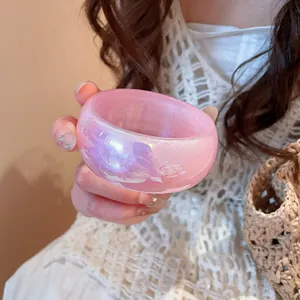 Vista detallada de un brazalete ancho transparente rosa iridiscente con efecto holograma