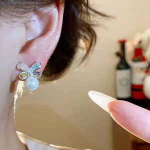 Close-up showing the detail of elegant flower zircon earrings with a white pearl drop on ear