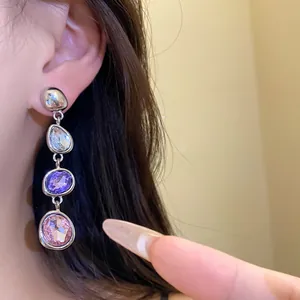 Dettaglio di orecchini pendenti in argento con pietre ovali bianche, viola e rosa