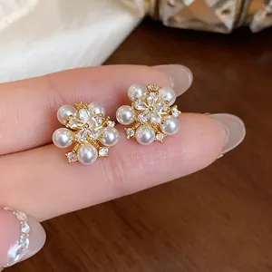 Close-up view of elegant flower stud earrings featuring white pearls and zircons
