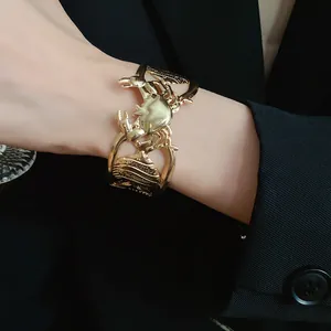 Close-up of a gold vintage cuff bracelet with hollow crab fish and seashell motifs