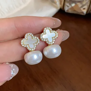Macro detail view of elegant four-leaf clover pearl earrings with sparkling zircon inlay