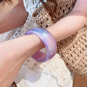 Primer plano de pulsera de resina morada irisada en la muñeca para un look de verano.