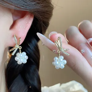Close-up of elegant bow and pearl flower earrings showing delicate zirconia detail.