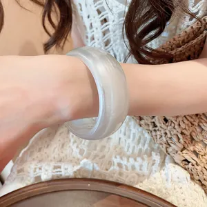 Primer plano de un brazalete ancho de resina holográfica iridiscente en una muñeca