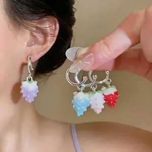 Hand holding colorful strawberry drip oil hoop earrings in a sweet summer fashion style