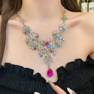 Gros plan d'un collier vintage avec cristaux colorés et pendentif goutte rose vif.