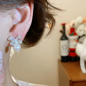 Macro detail of butterfly pearl earring with glittering cubic zirconia on model ear