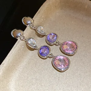 Dettaglio di orecchini a goccia in argento con cristalli ovali rosa e viola.