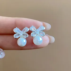 Elegant butterfly shaped zircon earrings with dangling white pearl detail shown in close-up view