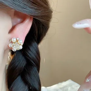 Close-up of elegant flower pearl stud earrings with zircons on model's ear