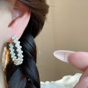 Close-up of elegant French style pearl hoop earrings with zircon accents on ear
