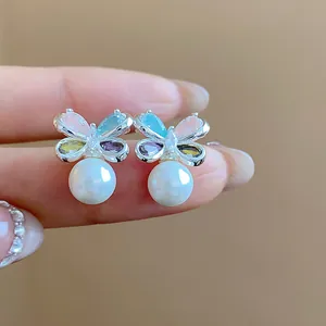Close-up of butterfly stud earrings with colorful zircon and pearl details