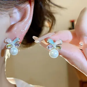 Close-up detail of elegant butterfly stud earrings with colorful zircons and a white pearl