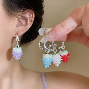 Macro detail of colorful enameled strawberry drop earrings in blue, pink, and red