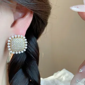 Close-up detail of elegant French style square earrings with pavé zircons and pearls on ear