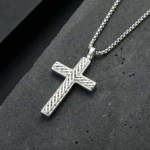 Close-up detail of silver stainless steel cross pendant with diagonal woven pattern