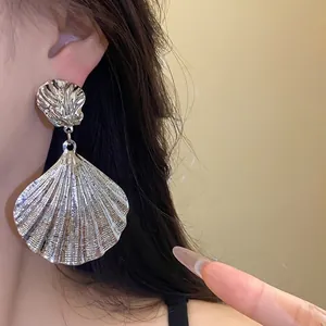 Statement silver pleated shell pendant earrings with vintage metallic finish on model