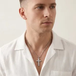Close-up of men's stainless steel cross necklace with diagonal texture worn by model.