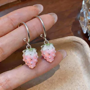 Close-up of pink enamel strawberry drop earrings with silver-tone hoops