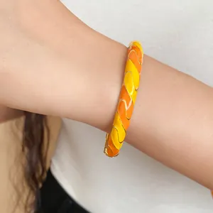 Vista ravvicinata del bracciale rigido vintage in resina con motivo a onde arancioni e gialle