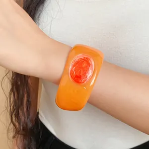 Primo piano di un bracciale vintage in resina arancione con trama marmorizzata e smalto