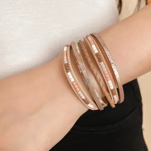 Dettaglio di bracciale boho multistrato con perle di resina e finitura metallica.