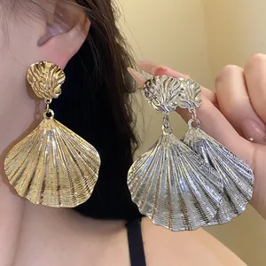 Detailed view of oversized gold and silver metallic seashell pleated dangle earrings