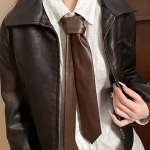 Detail shot of a dark brown retro leather necktie worn with a white shirt and jacket