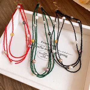 Detailed view of three layered beaded necklaces in red, green, and black with pearls.
