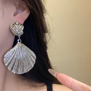 Detailed macro view of textured metallic shell drop earrings with shiny silver finish