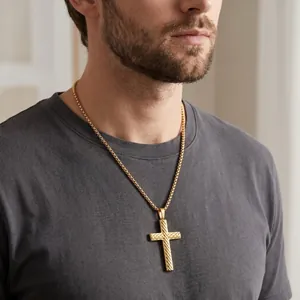 Close-up of gold stainless steel twill cross pendant on male model in gray t-shirt